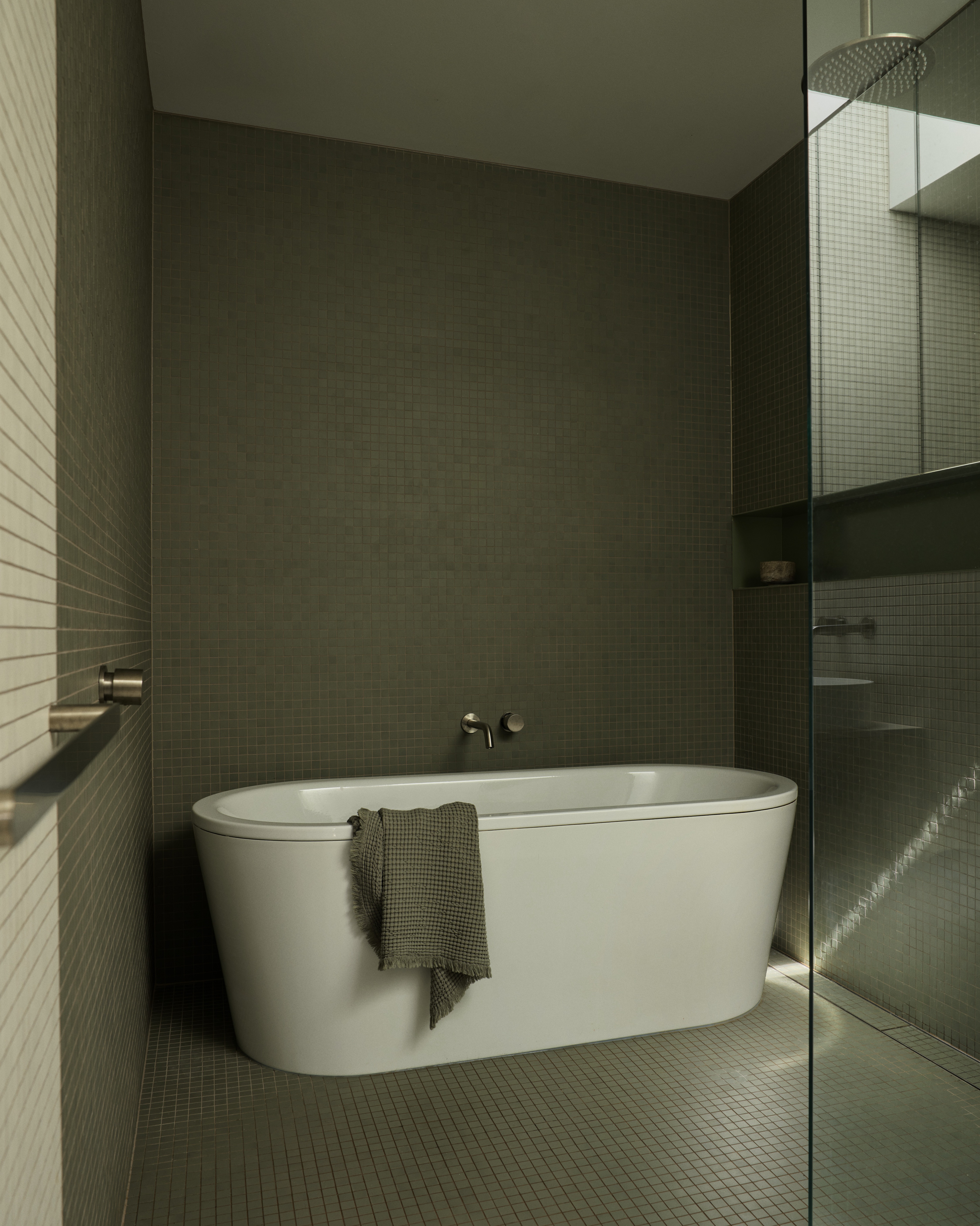 Olive mosaic-tiled bathroom with freestanding tub and glass shower